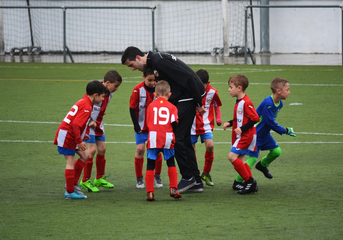 Trener omawia ćwiczenie z grupą kilkulatków na boisku